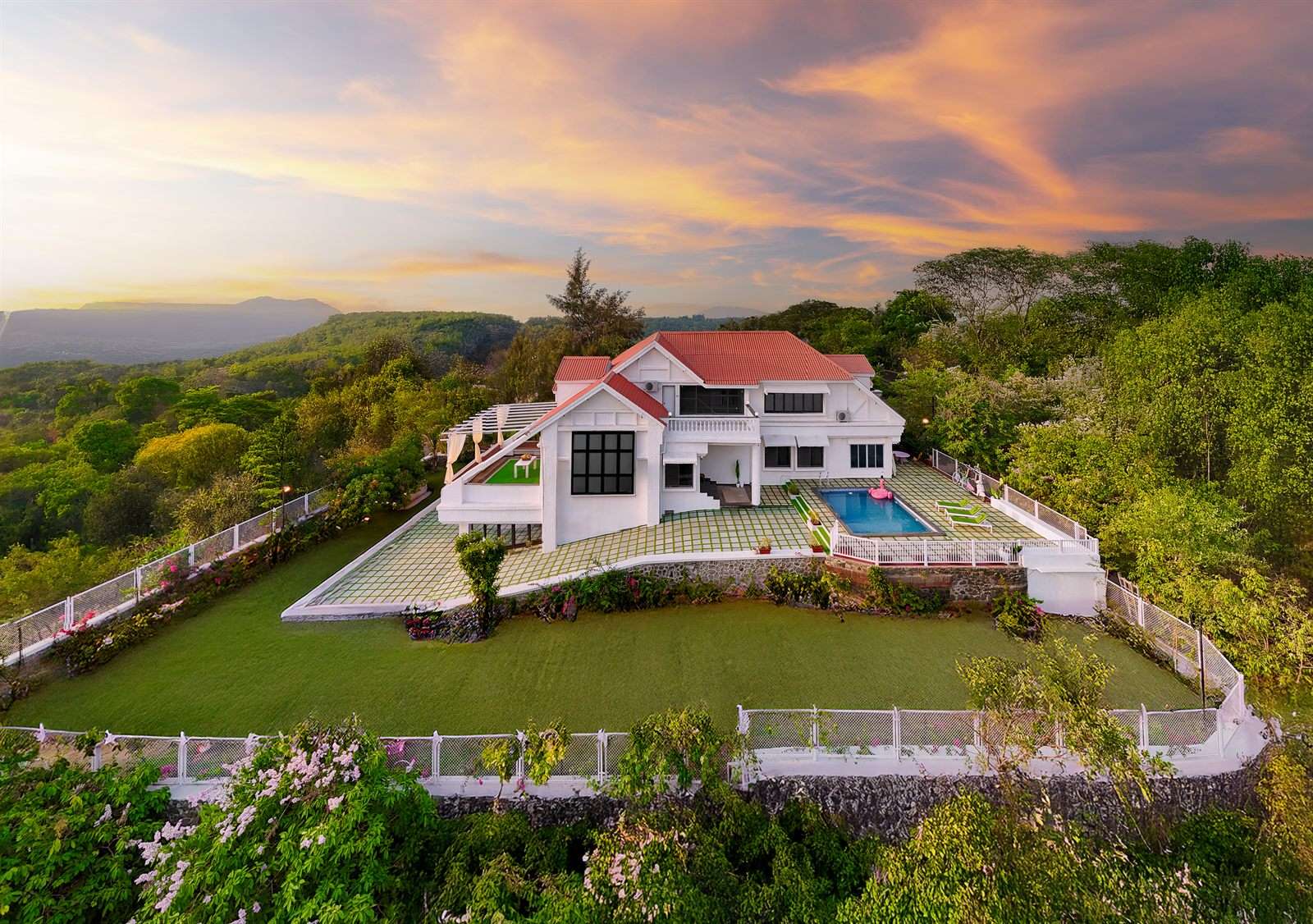 A hilltop EkoStay villa with a private pool and lawn overlooking a valley at sunset